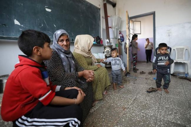 أسرة كردية نازحة تجلس في مدرسة عامة كمأوى لها بالحسكة بسوريا يوم الثلاثاء. تصوير: محمد حمد - رويترز